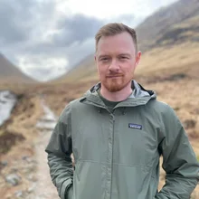 Will, who makes Perk, standing on a hill path in a green jacket.